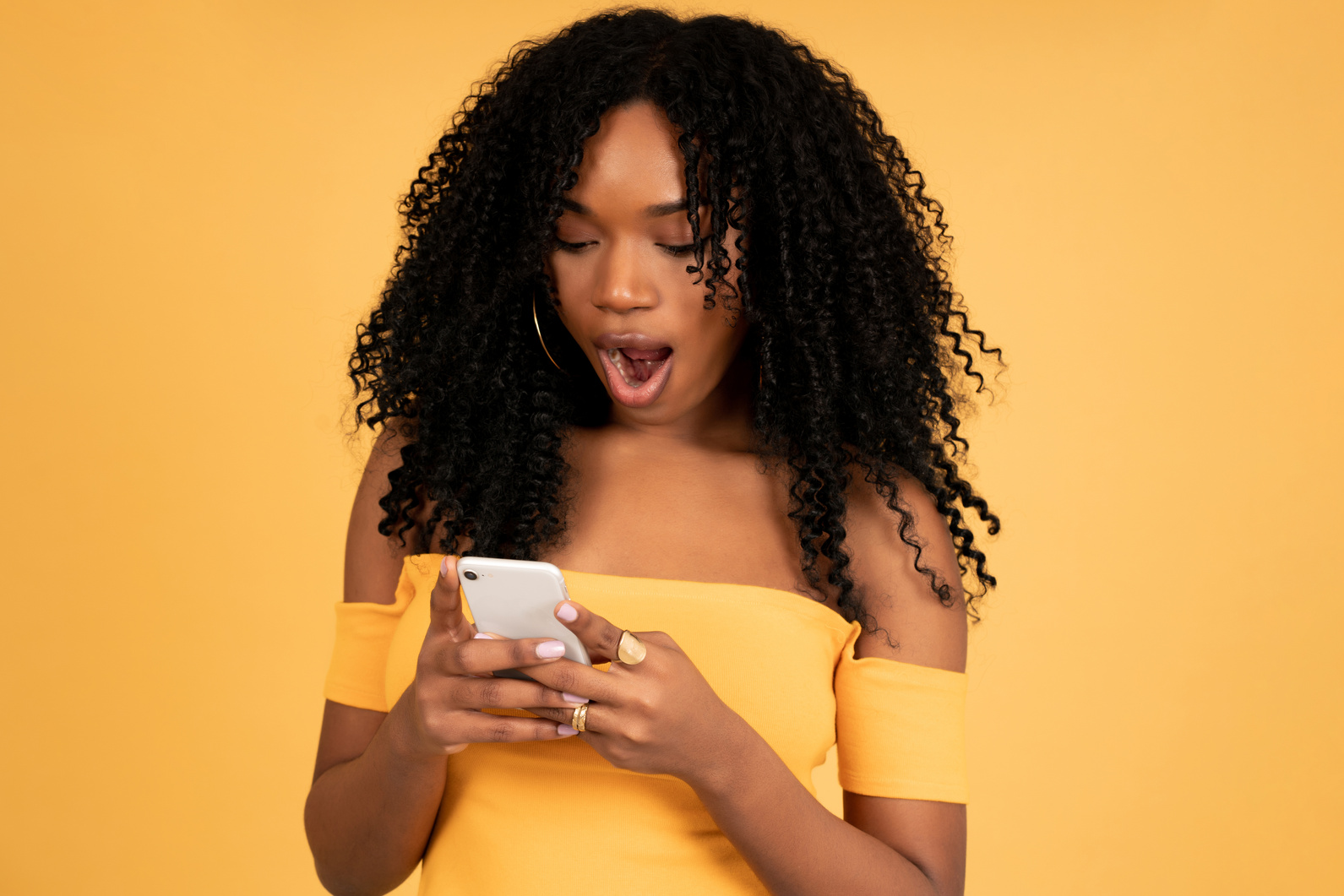 Afro Woman Looking at the Mobile Phone with Shocked Expression.